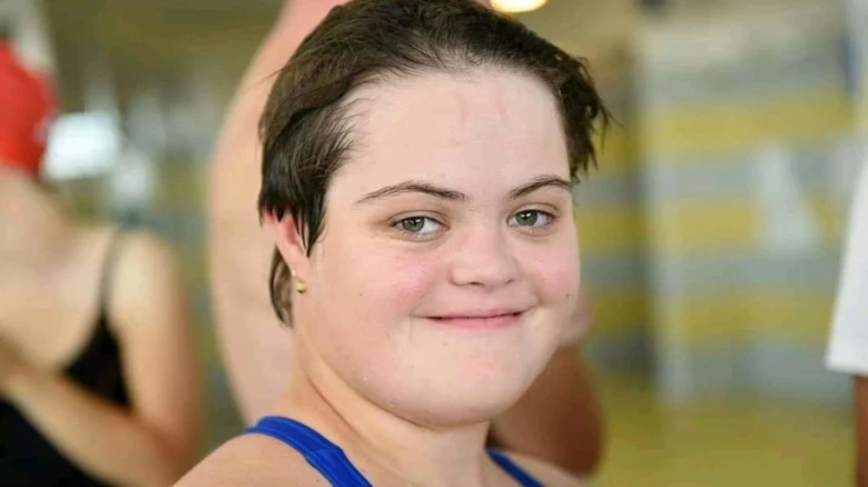 Usměvavá osoba s Downovým syndromem v modrém tričku.