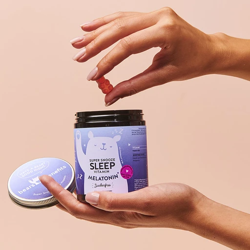 Ruka drží nádobku s vitamíny na spánek a bere žvýkačku.