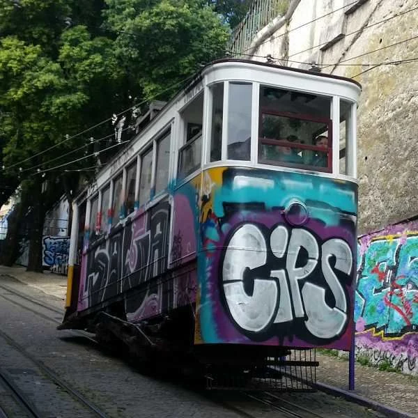 Starý žlutá tramvaj s grafiti v Lisabonu na kopci.