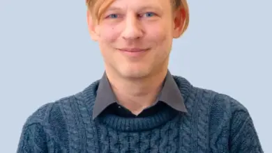 Muž v modrém svetrku na neutrálním pozadí.
