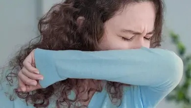 Žena s suchým kašlem zakrývá ústa rukou.