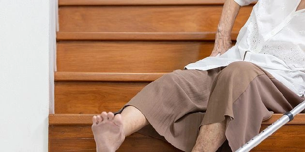 Elderly person on stairs with crutch