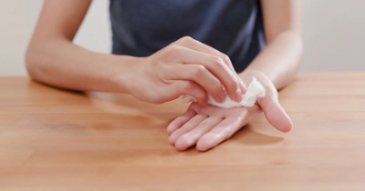 Osoba čistí ruku hadříkem pro hygienu rukou.
