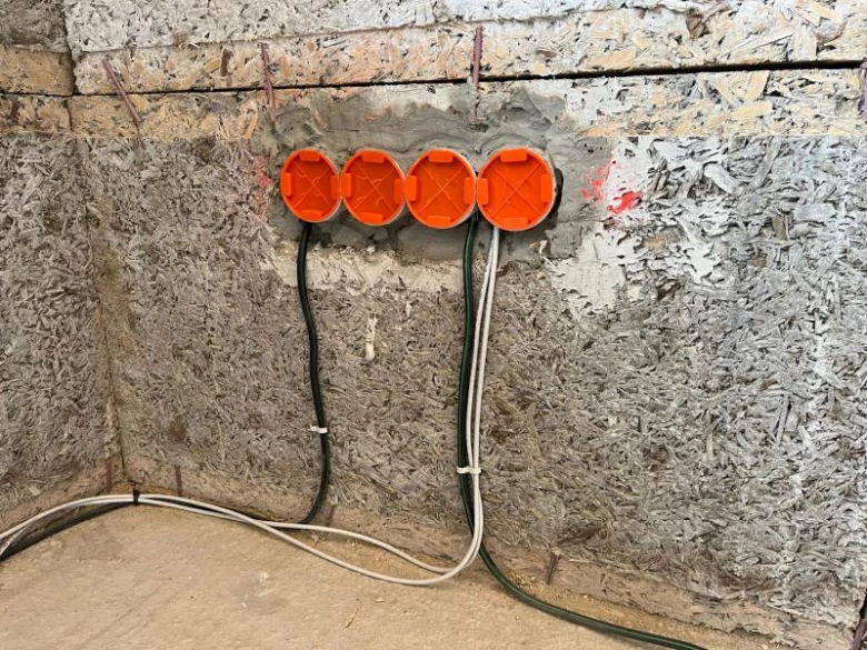 Oranžové kabelové vstupy na stěně během elektroinstalace.