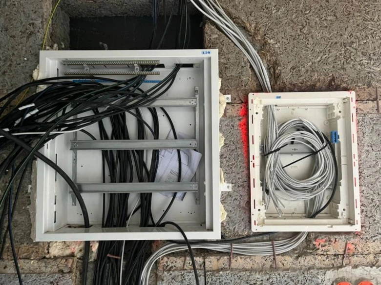 Dva otevřené elektrické rozvaděče s kabely během instalace v domě.