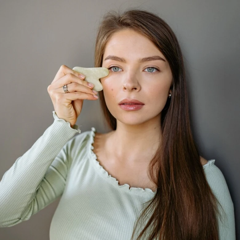 Žena používá kameň pro masáže obličeje na tvrdnutí pleti.