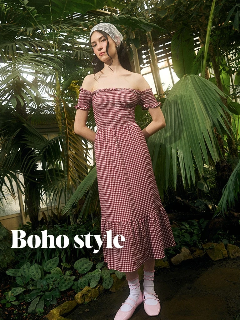 Žena v šatě boho stylu mezi tropickými rostlinami.