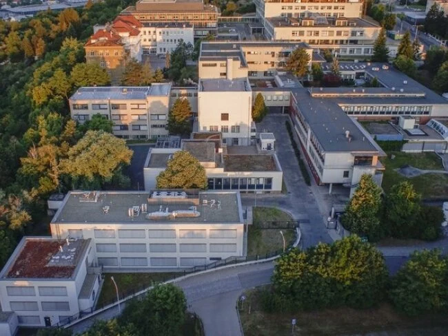 Vzdušný pohled na nemocniční komplex obklopený stromy.