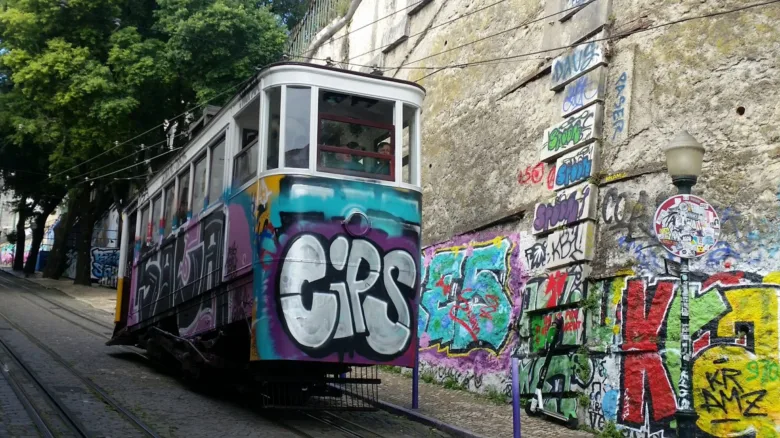 Starý tramvaj s grafiti v Lisabonu na kopci.