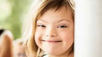Usměvavé dítě s downovým syndromem se dívá zpoza předmětu.