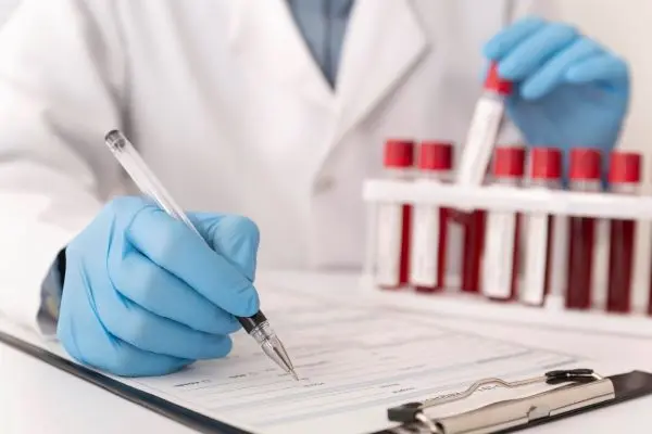 Lékař zapisuje výsledky krevních testů do formuláře.