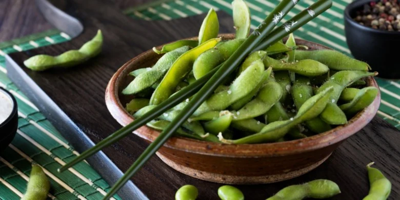 Mísa s čerstvými zelenými fazolemi edamame na bambusovém podkladu.