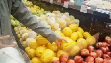 Ruce vybírají žluté ovoce z košíku v obchodě s potravinami.